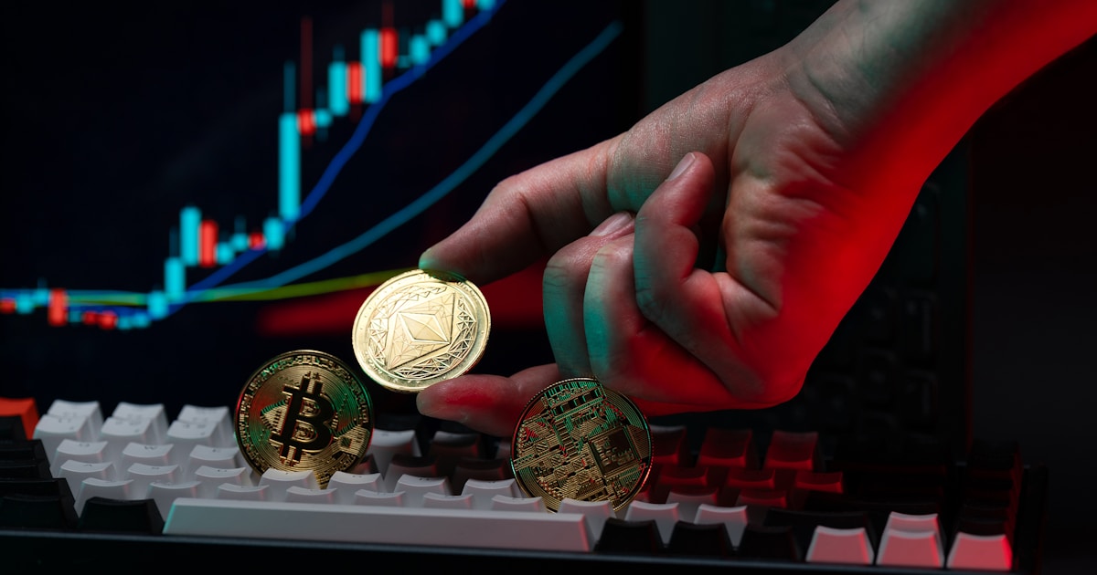 A person holding a coin in front of a computer keyboard