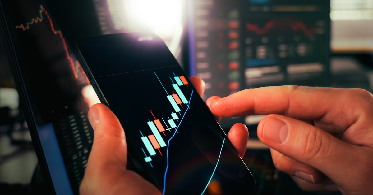 Hands holding smartphone showing stock market data