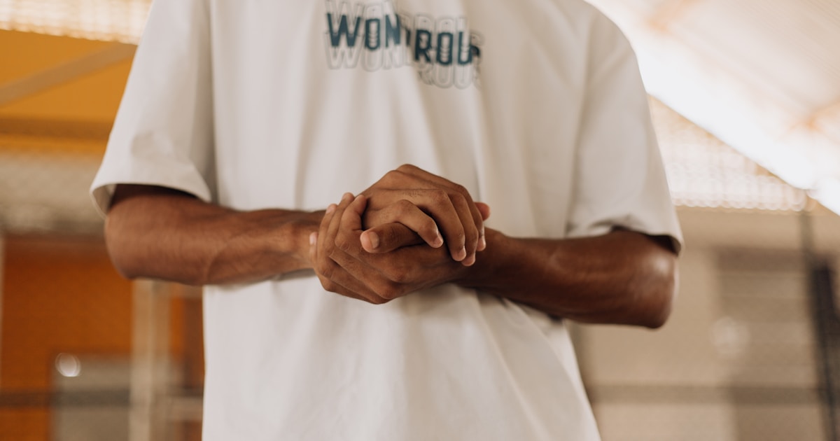 a man in a white shirt holding his hands together