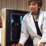 doctor sitting on desk talking to sitting woman
