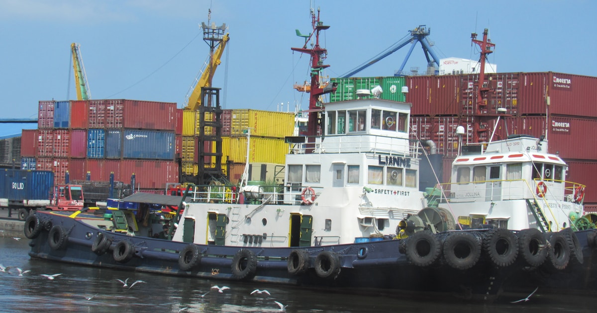 Real-World Use Cases of Blockchain Beyond Cryptocurrency 1 Tugboats docked at a busy shipping port with containers.