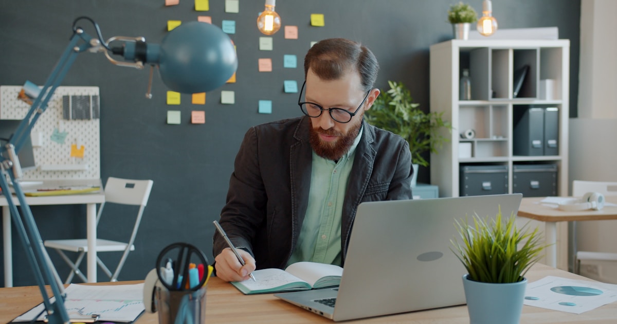 Top AI Tools Every IT Professional Should Learn in 2026 5 Man working at desk with laptop and notebook.