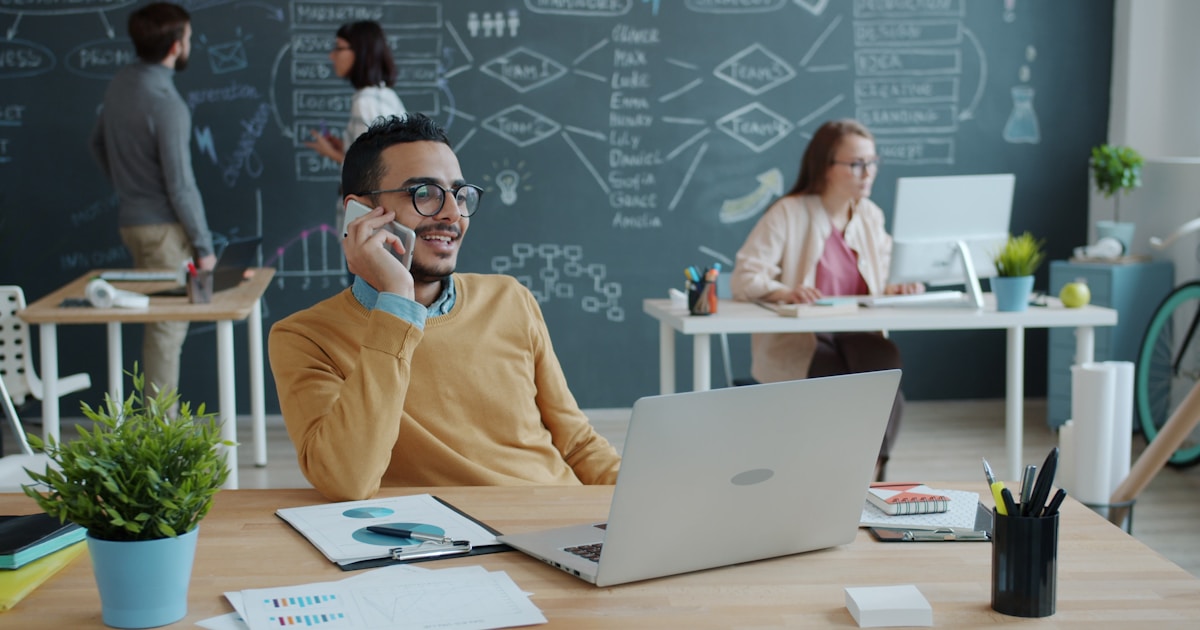 Future of Work with AI: How IT Pros Can Stay Relevant 4 Man talking on phone in modern office with team