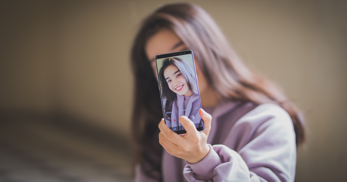 woman in white long sleeve shirt holding black smartphone